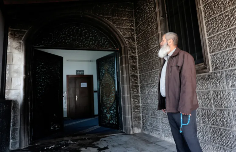 Un Palestinien, tenant des perles de prière Misbaha, inspecte les débris d'une mosquée, qui, selon les Palestiniens, a été endommagée par des colons israéliens, dans le village de Surra, en Cisjordanie, près de Naplouse, en Cisjordanie occupée par Israël, le 23 février 2026. REUTERS/Mohamad Torokman IMAGES TPX DU JOUR