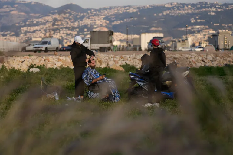 Amir Hajj, à gauche, un coiffeur déplacé par les frappes aériennes israéliennes à Dahiyeh, dans la banlieue sud de Beyrouth, coupe les cheveux d'un client sur la promenade du bord de mer de Beyrouth, le long de la mer Méditerranée, à Beyrouth,