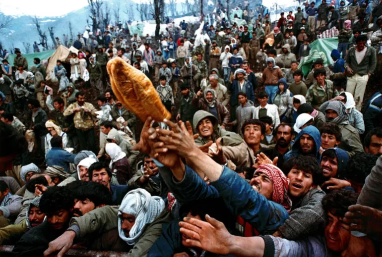 Les réfugiés kurdes frénétiques luttent pour une miche de pain lors d'une distribution d'aide humanitaire à la frontière irako-turque, le 5 avril 1991. REUTERS/Yannis Behrakis/RECHERCHE de photos de fichiers "YANNIS BEHRAKIS" FO
