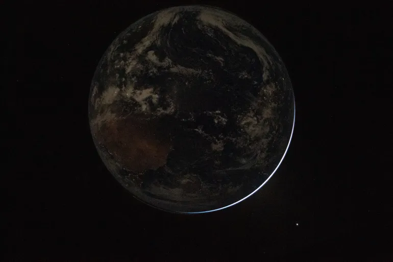 Cette photo fournie par la NASA montre une vue d'une Terre rétroéclairée vue à travers la fenêtre du vaisseau spatial Orion.