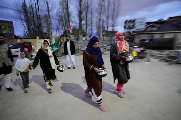 Des femmes musulmanes chiites arrivent avec des ustensiles de cuisine à donner lors d'une campagne de secours pour l'Iran à Budgam, au Cachemire sous contrôle indien, le lundi 23 mars 2026. (AP Photo/Mukhtar Khan)