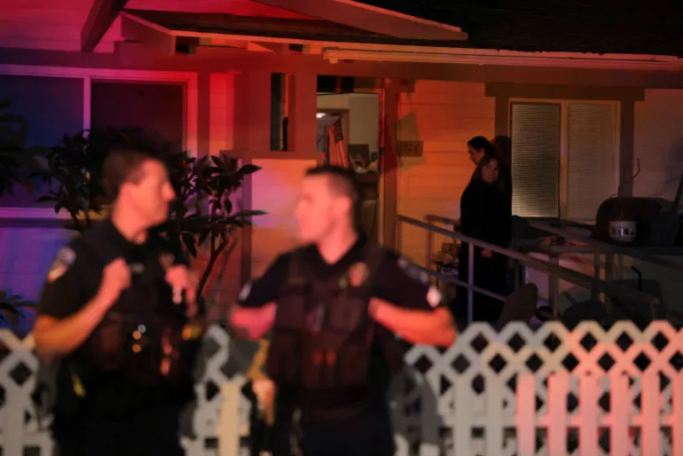 Les gens du quartier regardent la police se tenir au coin de la résidence associée à Cole Tomas Allen, le suspect de la fusillade lors du dîner annuel de l'Association des correspondants de la Maison Blanche à Washington, DC, à Torrance, Californie, États-Unis, le 25 avril 2026. REUTERS/Daniel Cole