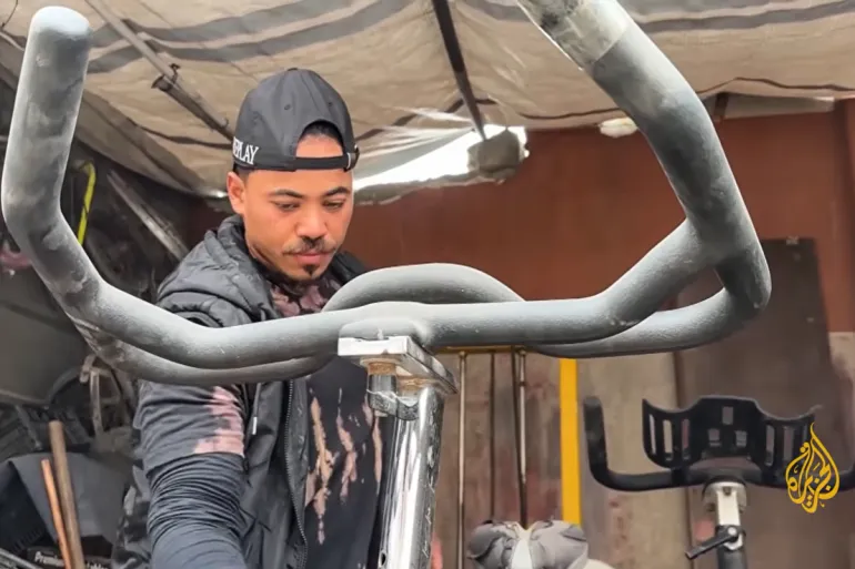 Muhannad Qasem, entraîneur physique et propriétaire d'une salle de sport, a été contraint de vendre les quelques pièces d'équipement qu'il avait récupérées dans les décombres de la rue pour nourrir sa famille. [Screengrab/Al Jazeera]