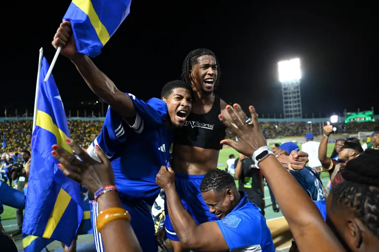 TOPSHOT - Les joueurs et les supporters de Curaçao célèbrent la qualification pour la Coupe du monde 2026 après un match nul 0-0 contre la Jamaïque au stade national de Kingston, en Jamaïque, le 18 novembre 2025.