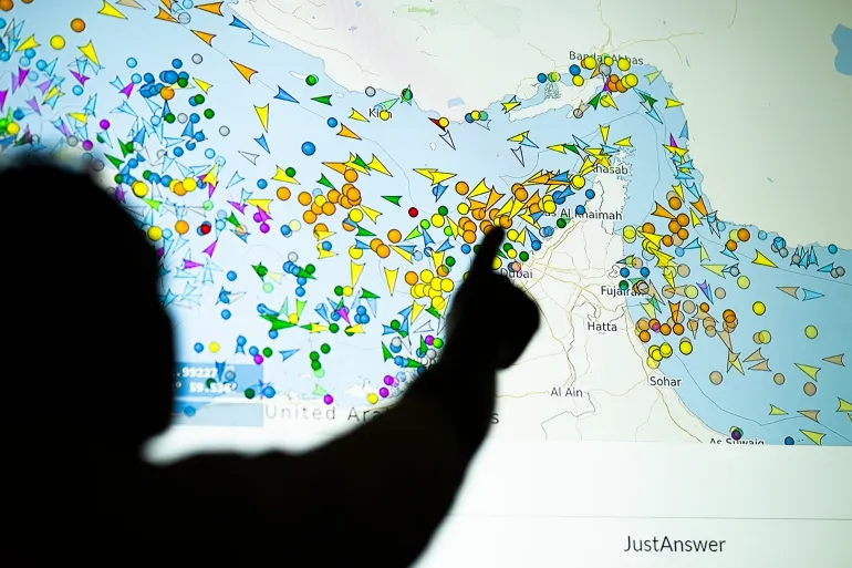 TOPSHOT - Une illustration photographique prise à Nicosie le 4 mai 2026 montre une personne devant un grand écran affichant les mouvements des navires dans le détroit d'Ormuz sur un site Web de suivi des navires.