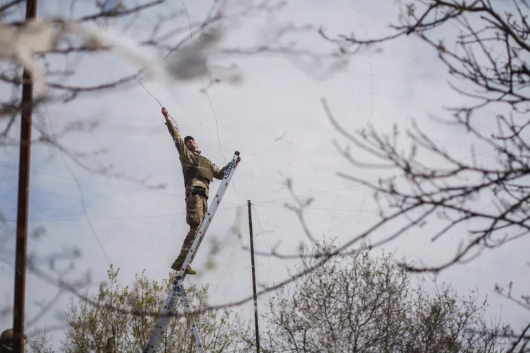 Un militaire des forces armées ukrainiennes installe des filets anti-drones sur une route près de la ville de première ligne de Druzhkivka, dans le contexte de l'attaque russe contre l'Ukraine, dans la région de Donetsk, en Ukraine le 28 avril 2026. REUTERS/Serhii Korovainyi IMAGES TPX DU JOUR