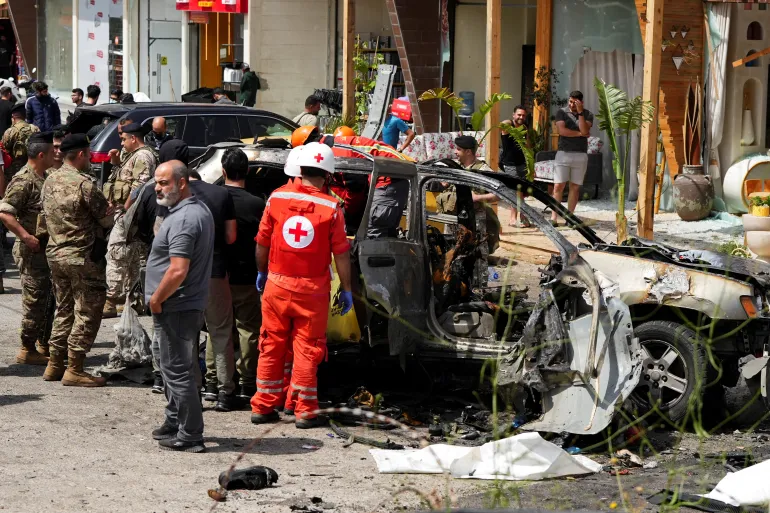 Les secouristes travaillent sur le site d'une frappe israélienne contre une voiture à Jiyeh