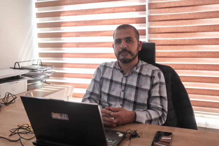 L'homme est assis au bureau avec un ordinateur portable ouvert
