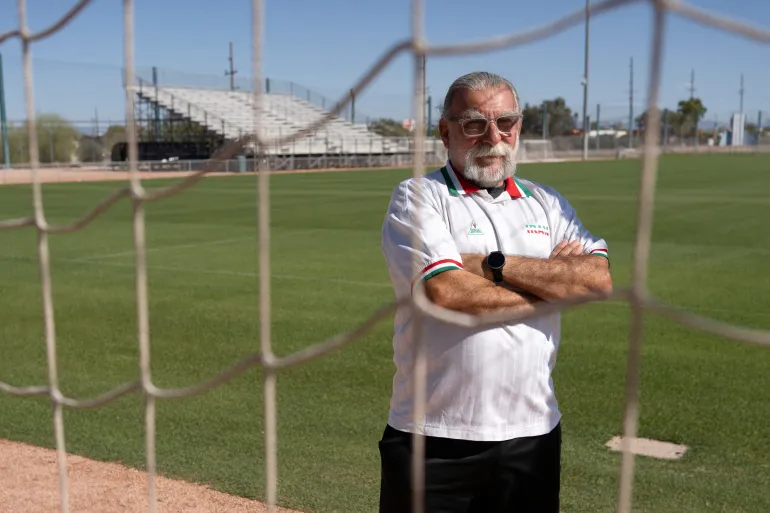 Amir Pajouyan, membre de la diaspora iranienne à Tucson, pose portant un maillot iranien au complexe sportif Kino, où l'équipe nationale iranienne de football, Team Melli, s'entraînera lors de la Coupe du monde de football 2026, à Tucson, en Arizona, le 6 mai 2026. Dans le détroit d'Ormuz, des navires de guerre américains menacent les pétroliers iraniens. À Washington, le président Donald Trump ne menace rien de moins que "victoire complète" suffira. Mais à Tucson, on s'apprête à accueillir l'équipe iranienne de football comme si de rien n'était. La ville, une oasis de pelouses bien entretenues dans le désert de l'Arizona, devrait devenir le camp de base pour "L'équipe Melli" lorsque le plus grand spectacle sportif du monde s'ouvrira aux États-Unis, au Mexique et au Canada le mois prochain. (Photo de Rebecca NOBLE / AFP)