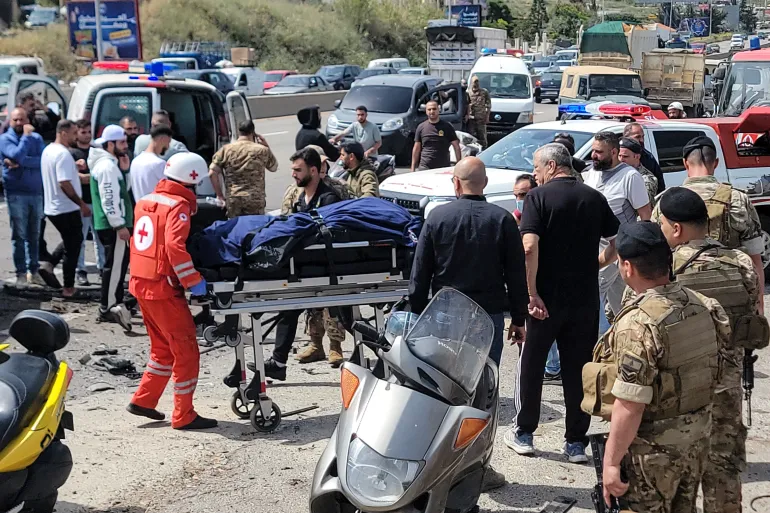 Les premiers intervenants transportent le corps d'une victime sur le site d'une frappe de drone israélien qui a visé un véhicule dans la ville de Jiyeh