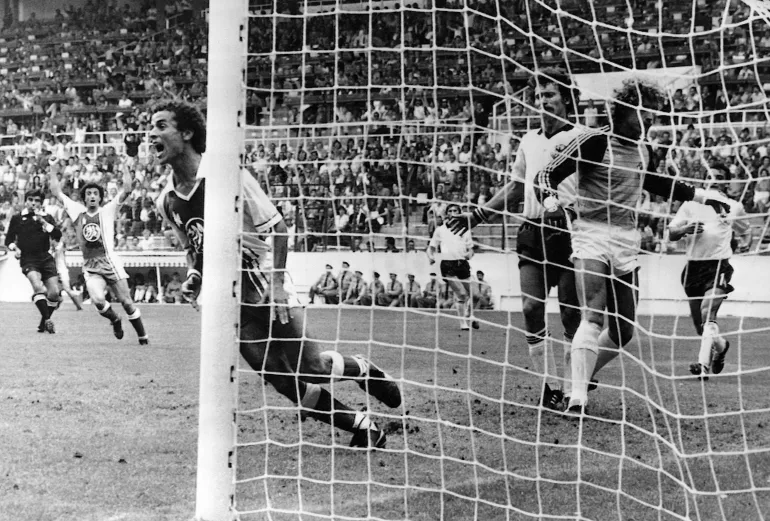 Sur cette photo d'archive du 16 juin 1982, l'Algérien Lakhdar Belloumi, à gauche, célèbre après avoir marqué le deuxième but vainqueur de son équipe lors du match de la Coupe du monde de football.