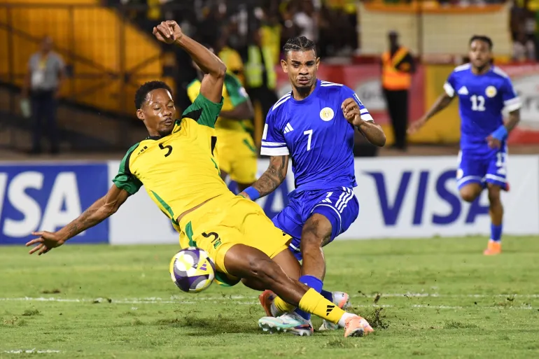 Juninho Bacuna de Curaçao, au centre, se bat pour le ballon contre Ethan Pinnock, de la Jamaïque, à gauche, lors d'un match de football de qualification pour la Coupe du monde 2026 à Kingston, en Jamaïque, le mardi 18 novembre 2025. (AP Photo/Collin Reid)