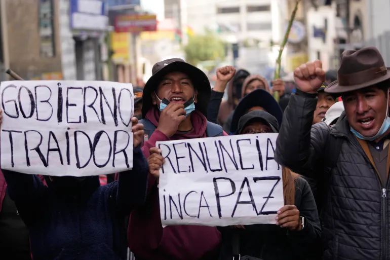 Des manifestants antigouvernementaux brandissent des pancartes indiquant en espagnol "Démissionne Paz," et "Gouvernement traître" faisant référence au président Rodrigo Paz à La Paz, Bolivie, le lundi 18 mai 2026