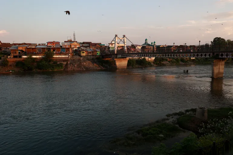 People walk on a bridge built on the River Jhelum in Sopore, Jammu and Kashmir, India, on May 7, 2026. The Jhelum River flows through India and Pakistan under the framework of the Indus Water Treaty, with recent tensions and border conflicts renewing scrutiny over its water-sharing provisions. (Photo by Nasir Kachroo/NurPhoto via Getty Images)