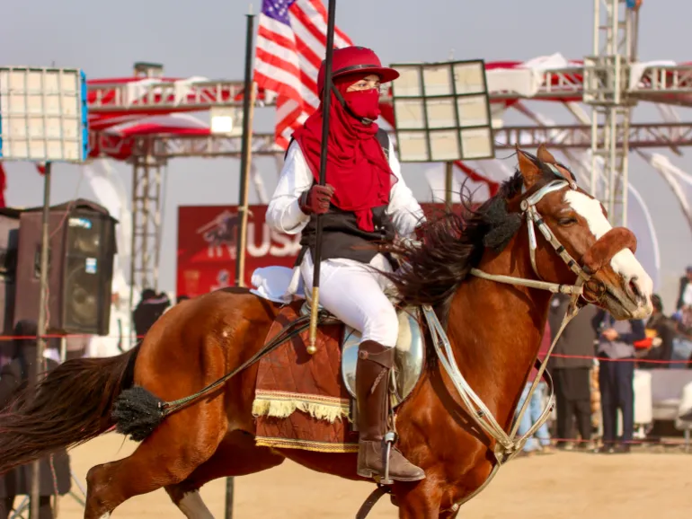 A female rider, Sehrish Awan, straightens her lance as she gears up for competition in a mela organised by a USA-based riding club [Mutee Ur Rehman/ Al Jazeera]