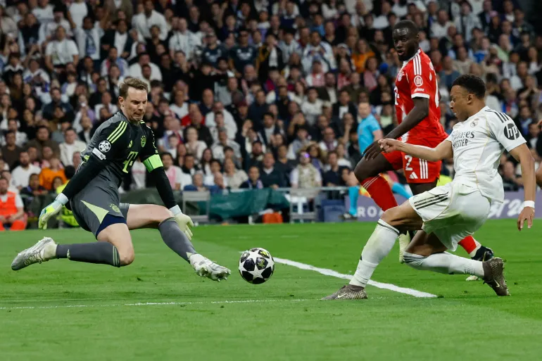 TOPSHOT - L'attaquant français n°10 du Real Madrid Kylian Mbappe (R) tire mais ne parvient pas à dépasser le gardien de but allemand n°01 du Bayern Munich Manuel Neuer lors du quart de finale de la Ligue des champions de l'UEFA, match aller entre le Real Madrid CF et le FC Bayern Munich au stade Santiago Bernabeu de Madrid le 7 avril 2026.