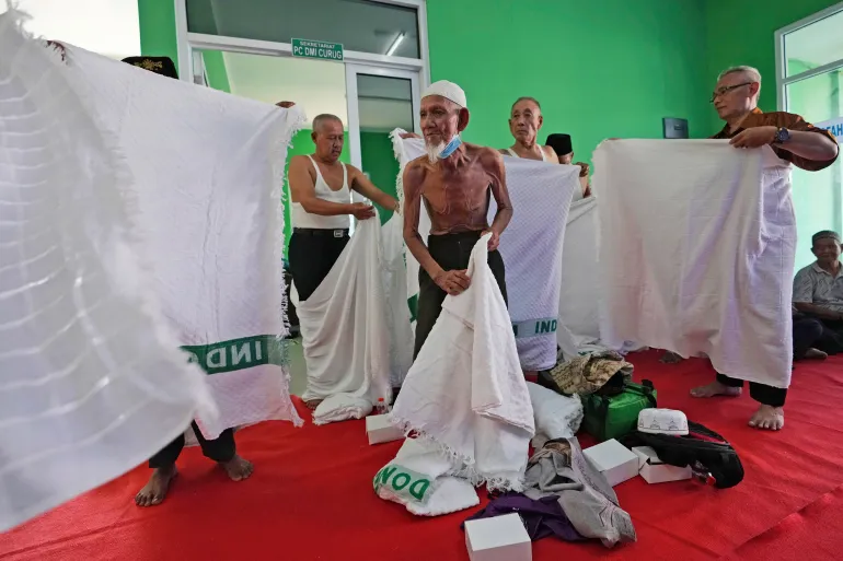 Husin bin Nisan, au centre, avec d'autres fidèles, se prépare à porter un costume spécial appelé "Ihram," généralement porté pendant le pèlerinage du hajj, avant une répétition du hajj à Tangerang, Indonésie, le lundi 15 mai 2023. Après avoir passé plus de trois décennies à recueillir des conseils auprès des automobilistes, l'agent de circulation bénévole de 85 ans réalise enfin son rêve d'aller dans les villes saintes islamiques de La Mecque et de Médine pour le pèlerinage du hajj. (Photo AP/Achmad Ibrahim)