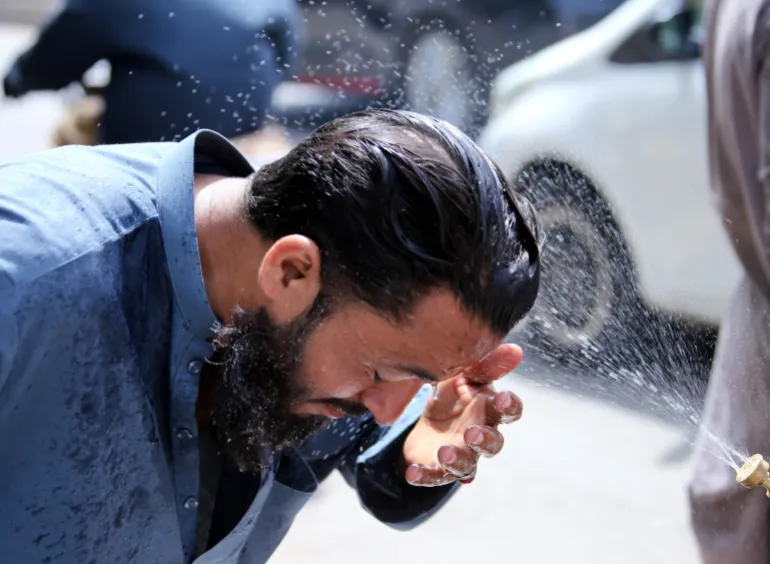 epa12934290 Un volontaire pulvérise de l'eau sur les gens pour se rafraîchir pendant une vague de chaleur à Karachi, au Pakistan, le 5 mai 2026. Karachi devrait rester chaud et sec au cours des prochaines 24 heures, avec des températures inférieures à 40 degrés Celsius, a déclaré le Département météorologique du Pakistan, après un pic de 44,1 degrés Celsius, car il est conseillé aux habitants de limiter leur exposition et de rester hydratés. EPA/REHAN KHAN