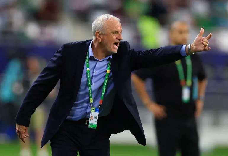 Graham Arnold wearing a suit and pointing
