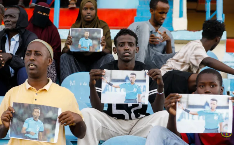 Les Somaliens détiennent des photos de l'arbitre Omar Abdulkadir Artan, qui devait arbitrer des matchs de la coupe du monde de la FIFA 2026 mais qui s'est vu refuser l'entrée aux États-Unis, lors d'un match entre Gaadiidka et Juba au stade de Mogadiscio, à Mogadiscio, en Somalie, le 9 juin 2026. REUTERS/Feisal Omar