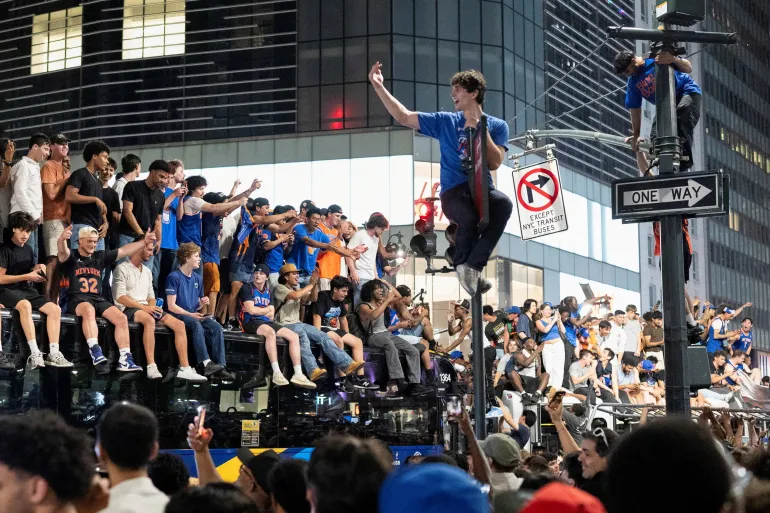 Les fans célèbrent la victoire des New York Knicks contre les San Antonio Spurs lors du jeu 5 des finales de la NBA, dans une rue près du Madison Square Garden, à New York, aux États-Unis, le 14 juin 2026. REUTERS/Christian Monterrosa