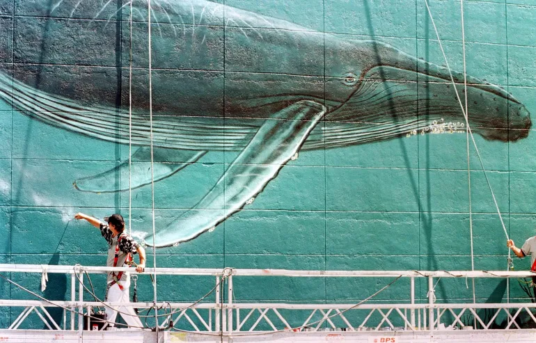 L'artiste de la vie marine Wyland utilise un petit pinceau pour mettre la touche finale à son interprétation d'une baleine à bosse dans une fresque murale de sept étages représentant des mammifères marins dans l'océan au centre-ville de Miami, le 30 avril. Wyland, qui peint des peintures murales sur des baleines et d'autres mammifères marins depuis 1981 et a réalisé 77 murs aux États-Unis, au Japon, en Australie, au Mexique et en France, participe actuellement à un projet de 30 ans visant à réaliser 100 peintures murales sur la vie marine d'ici 2011 dans le but d'accroître le soutien à la préservation de l'océan. PHOTO AFP Roberto SCHMIDT (Photo de ROBERTO SCHMIDT / AFP)