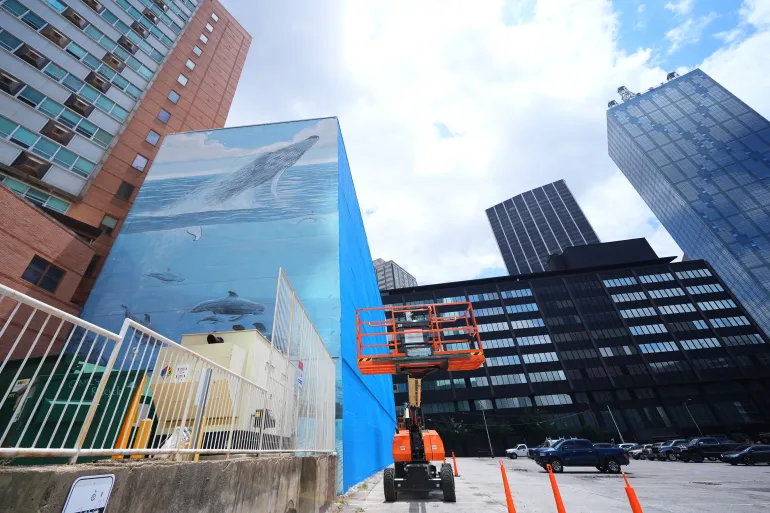 Une section d'une peinture murale, connue sous le nom de "Mur baleinier 82," créé par l'artiste Wyland, est visible car une partie de celui-ci sur le côté droit du bâtiment a été repeinte, le lundi 18 mai 2026, à Dallas. (Photo AP/Julio Cortés)