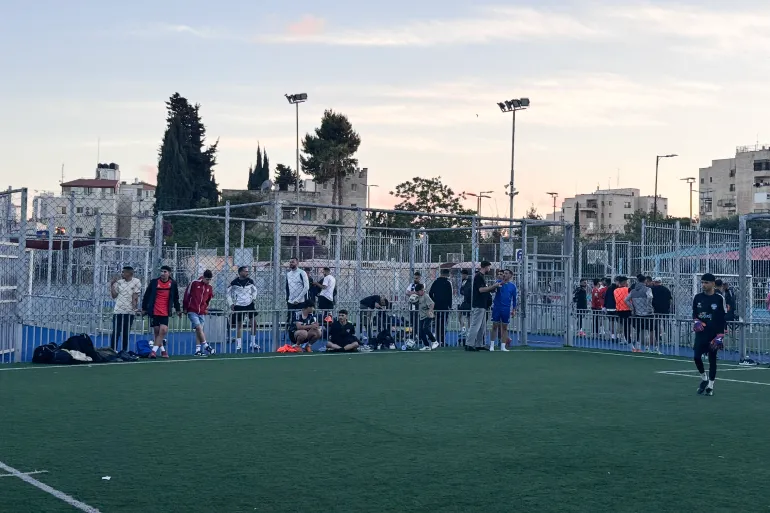 Photo au coucher du soleil de diverses personnes, dont des joueurs de l'équipe nationale, attendant de jouer pendant le tournoi de l'Aïd.