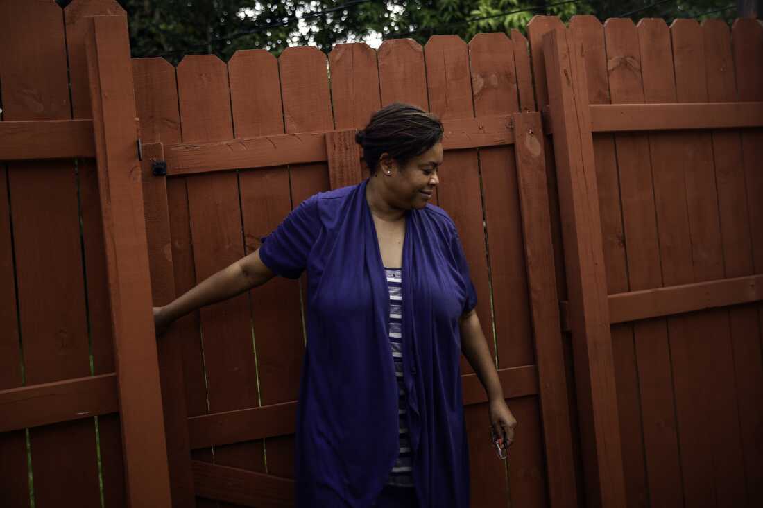 Farah Larrieux ferme derrière elle un grand portail en bois.