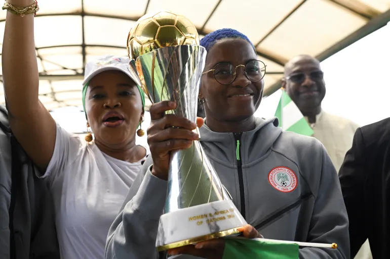 Le capitaine des Super Falcons du Nigeria, Rasheedat Ajibade, détient le trophée WAFCON 2024 sous les applaudissements de ses supporters à l'aéroport international Nnamdi Azikiwe d'Abuja.